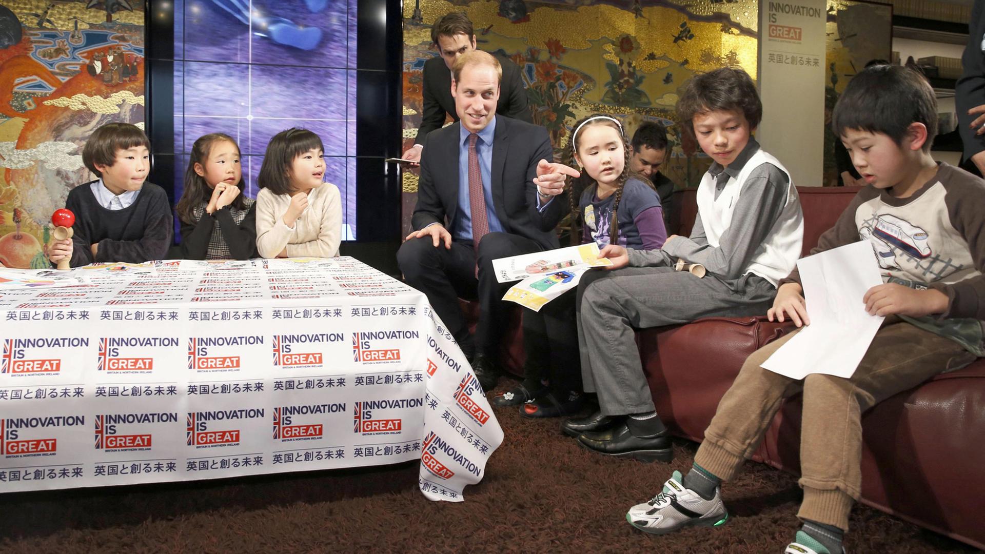 Der britische Prinz William spricht mit Kindern in einem Buchladen in Tokios Daikanyama-Viertel.