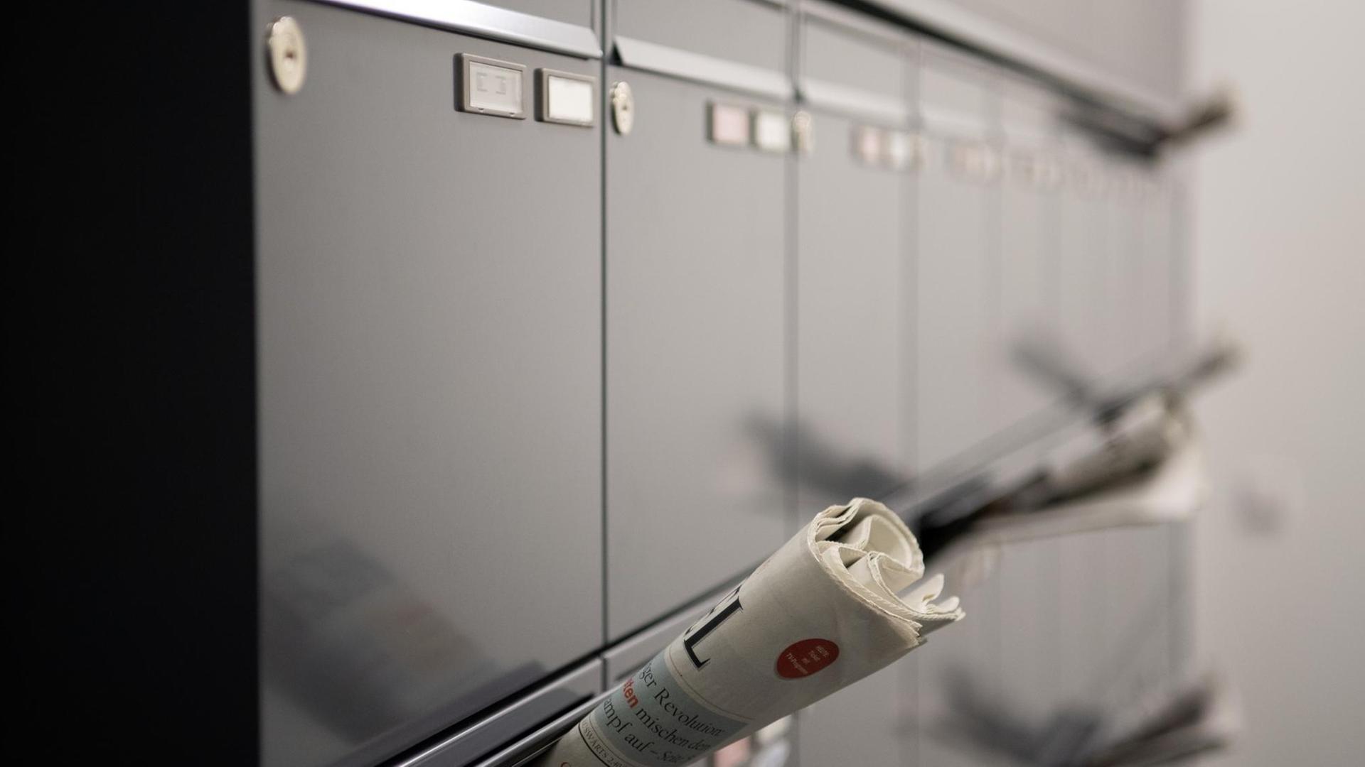 Mehrere Zeitungen stecken in Briefkästen im Flur eines Mehrfamilienhauses Mehrere Zeitungen stecken in Briefkästen im Flur eines Mehrfamilienhauses