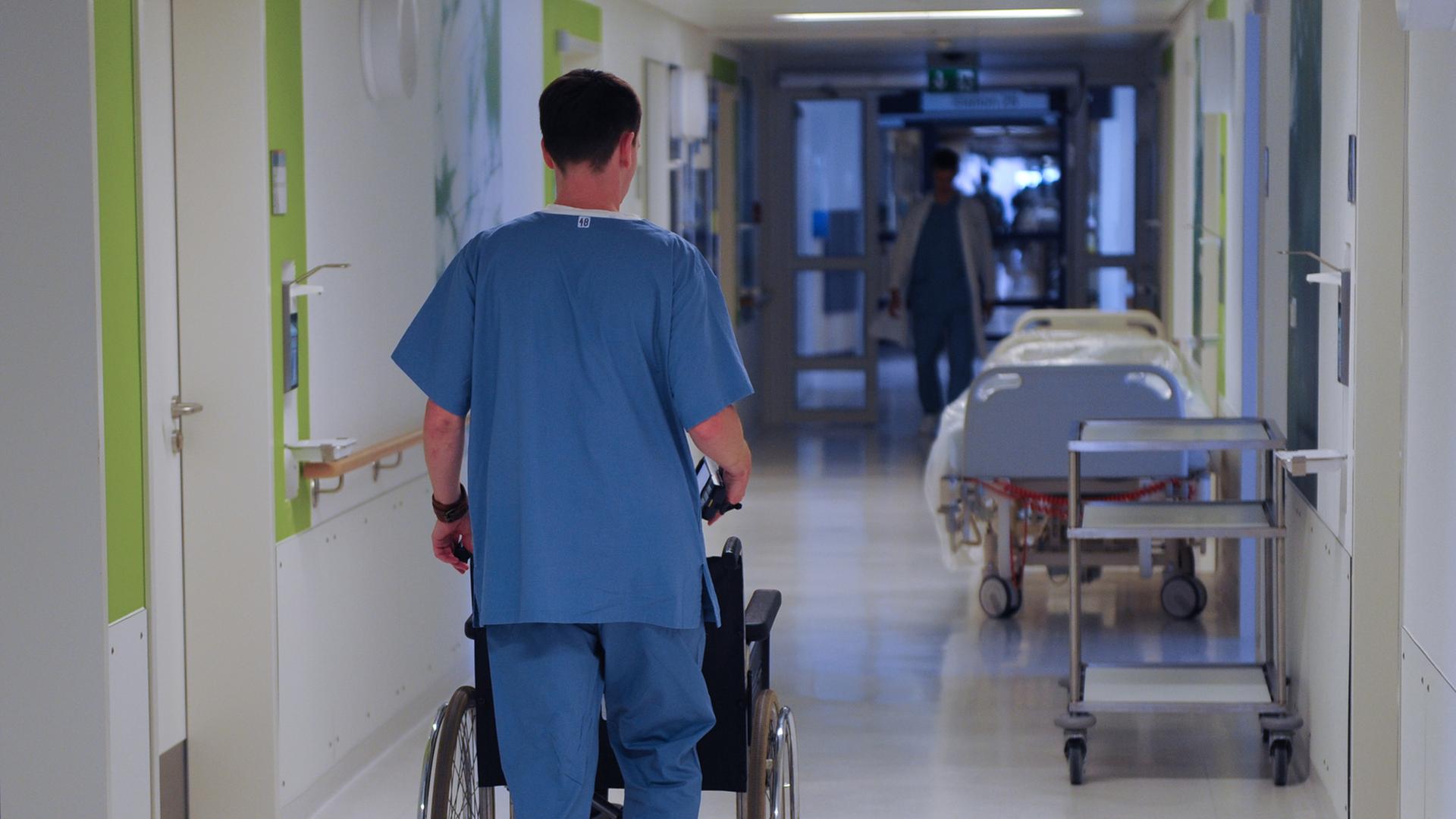 Ein Pfleger schiebt einen Rollstuhl durch einen Krankenhausflur. Ein Pfleger schiebt einen Rollstuhl durch einen Krankenhausflur.