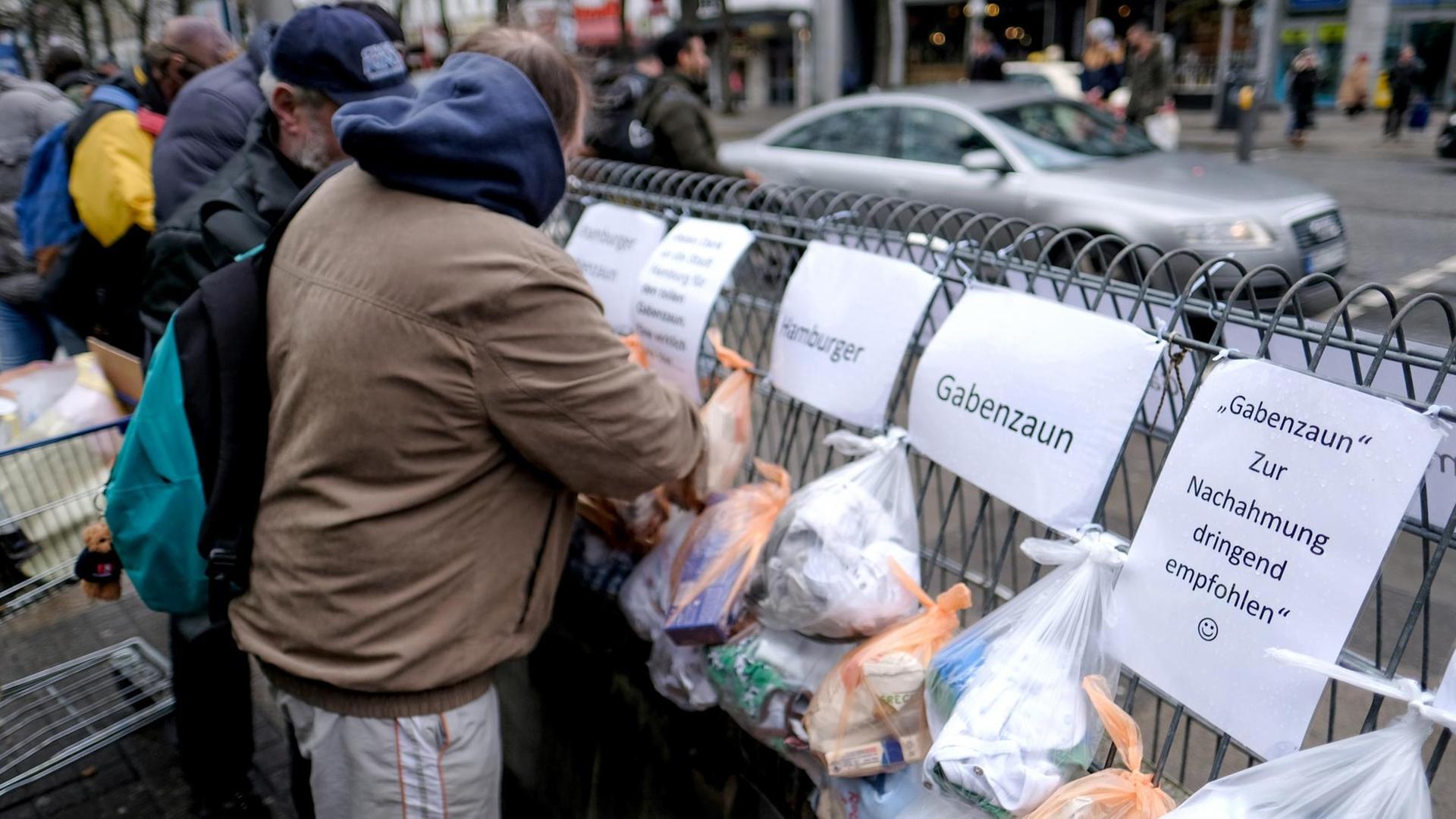 Obdachlose nehmen sich in Hamburg am Hauptbahnhof Essen und Kleidung vom Hamburger Gabenzaun. Obdachlose nehmen sich in Hamburg am Hauptbahnhof Essen und Kleidung vom Hamburger Gabenzaun.