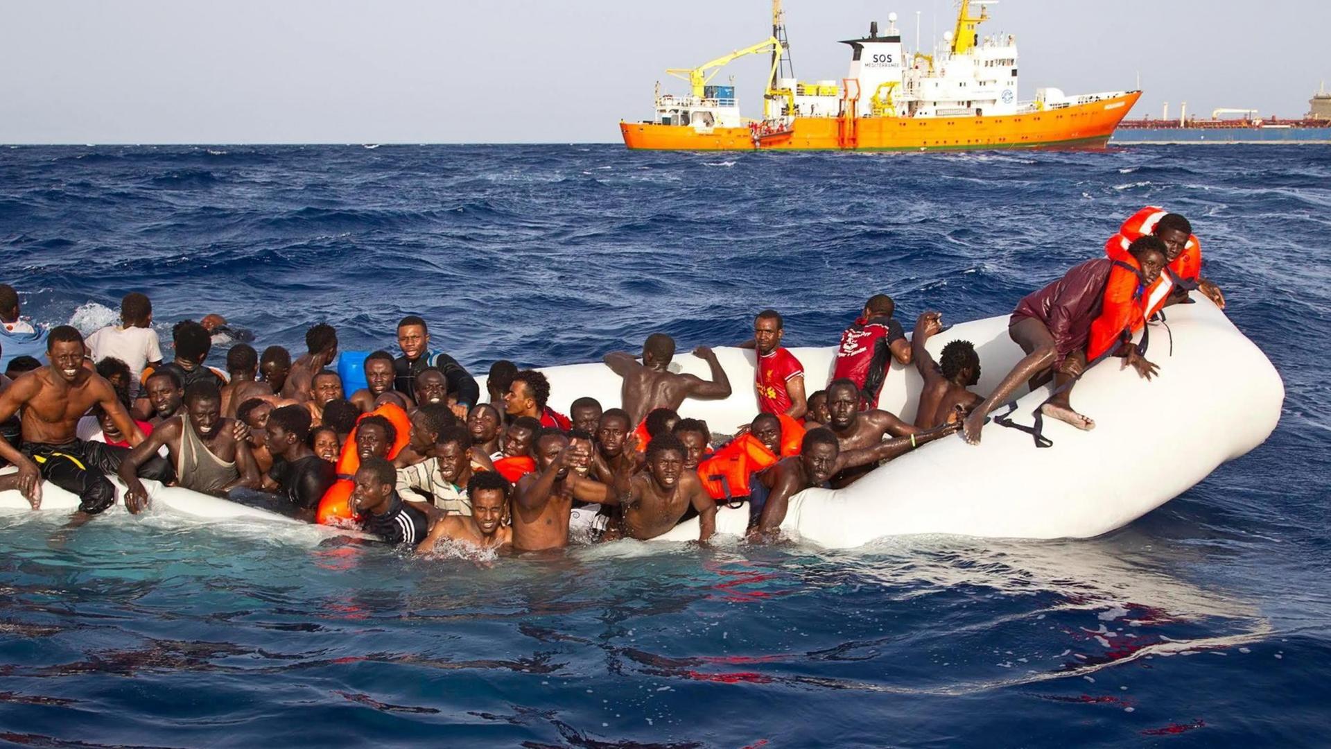 Ein Foto der Hilfsorganisation SOS Mediterranee zeigt Flüchtlinge in einem sinkenden Schlauchboot vor Lampedusa.
