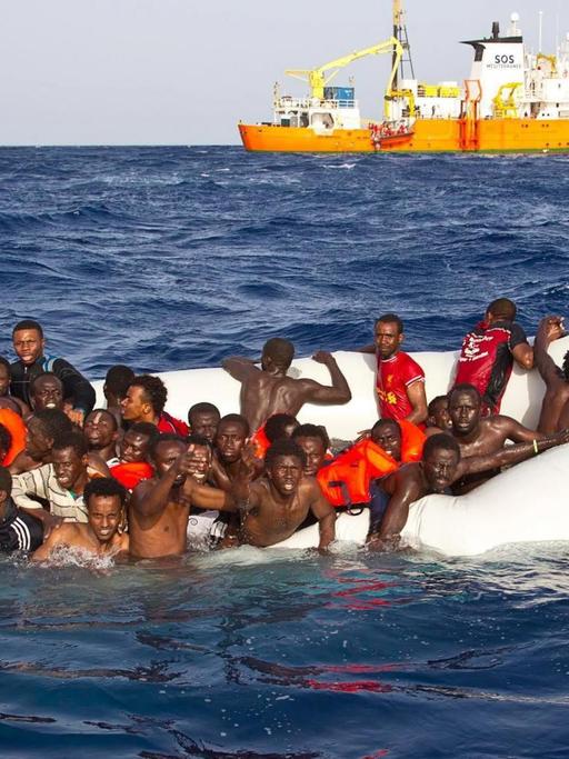 Ein Foto der Hilfsorganisation SOS Mediterranee zeigt Flüchtlinge in einem sinkenden Schlauchboot vor Lampedusa.