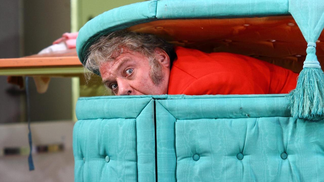 Falstaff (Bry Terfel) schaut verängstigt aus einer stoffbezogenen Kiste Falstaff (Bry Terfel) schaut verängstigt aus einer stoffbezogenen Kiste