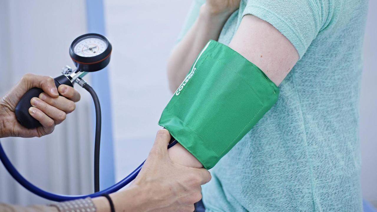Bei einer Patientin in einer Arztpraxis wird der Blutdruck gemessen.