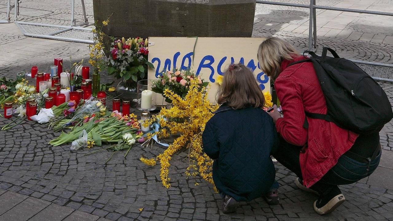 Eine Frau mit Kind an der Kiepenkerl-Statue in Münster, wo Trauernde Blumen ablegten