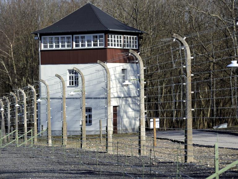 Ein zweistöckiger Wachturm hinter einem Stacheldrahtzaun.