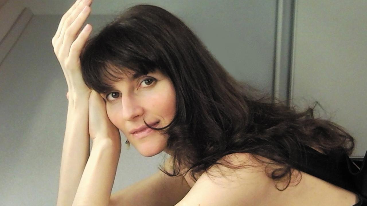Elisaveta Blumina stützt ihren Kopf in ihre Hände und lächelt. Elisaveta Blumina stützt ihren Kopf in ihre Hände und lächelt.