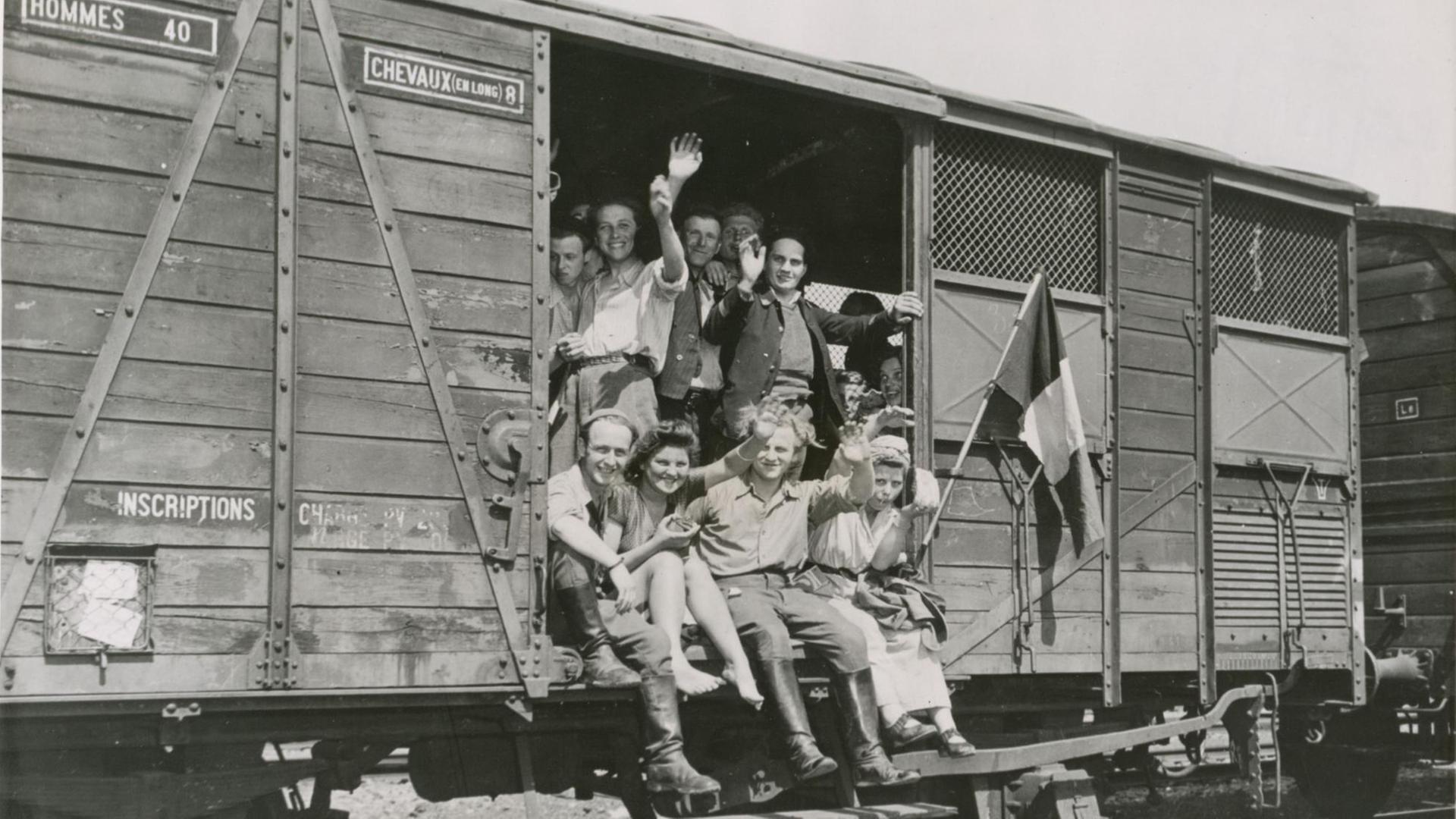 Französische Zwangsarbeiter winken nach der Befreiung durch die Alliierten aus einem Eisenbahnwaggon.