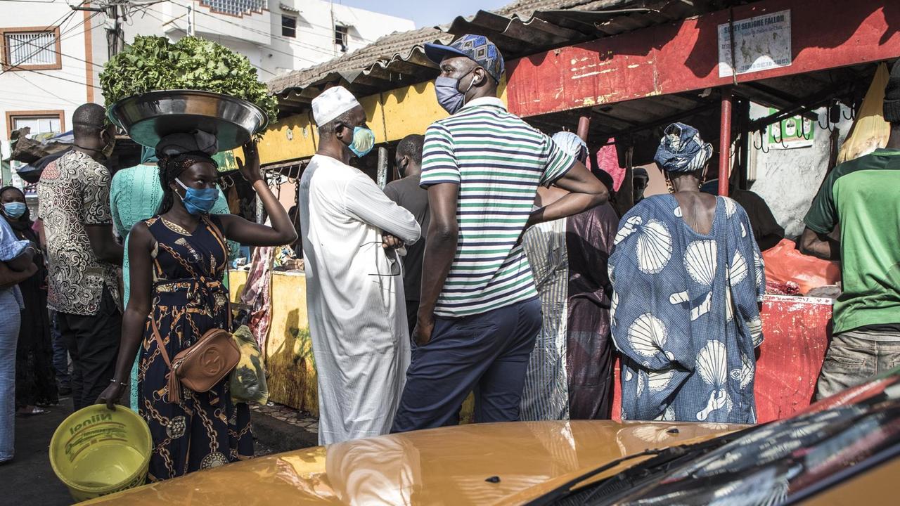 Senegalesen mit Atemschutzmasken beim Einkaufen auf einem Markt in Dakar. Senegalesen mit Atemschutzmasken beim Einkaufen auf einem Markt in Dakar.