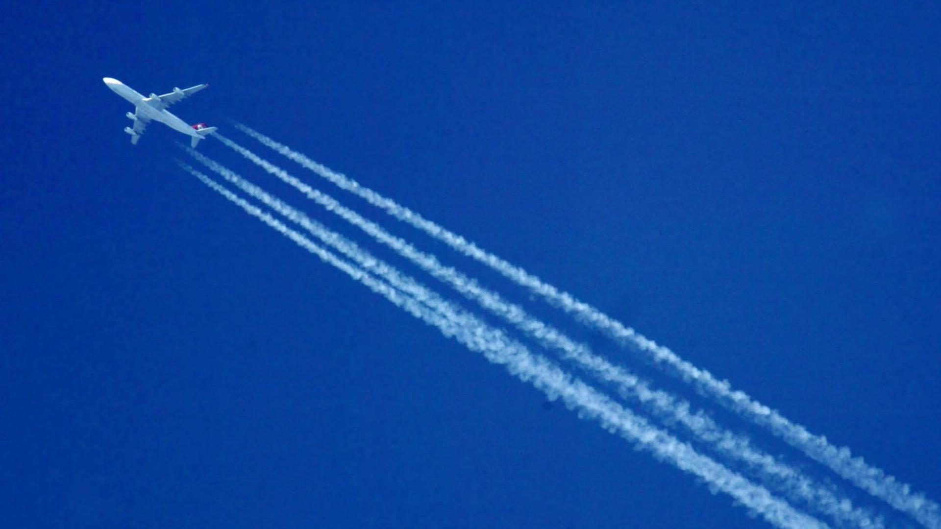 Ein Flugzeug hinterlässt Kondensstreifen vor einem blauen und wolkenlosen Himmel. Ein Flugzeug hinterlässt Kondensstreifen vor einem blauen und wolkenlosen Himmel.