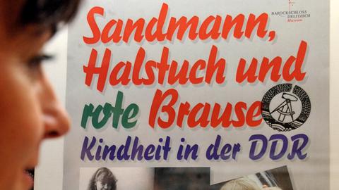 Auf das Plakat der Sonderausstellung mit dem Titel "Sandmann, Halstuch und rote Brause - Kindheit in der DDR" schaut eine Mitarbeiterin des Museums Barockschloss Delitzsch, aufgenommen am 26.11.2008 in Delitzsch bei Leipzig.