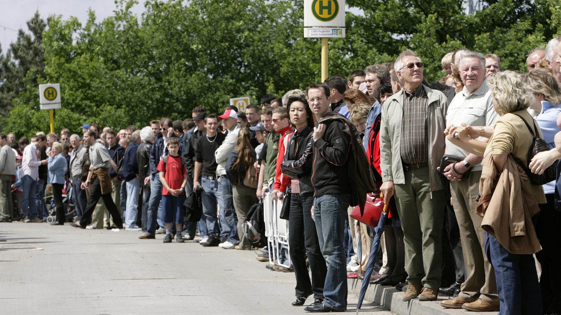 Viele Menschen stehen an einer Bushaltestelle. Viele Menschen stehen an einer Bushaltestelle.
