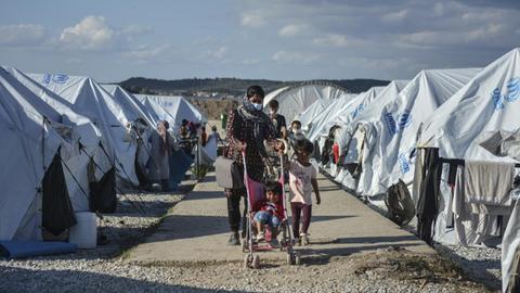 Eine Frau und Kinder laufen im Flüchtlingslager Kara Tepe auf der Insel Lesbos zwischen weißen Zelten entlang. (Aufnahme vom 14. Oktober)