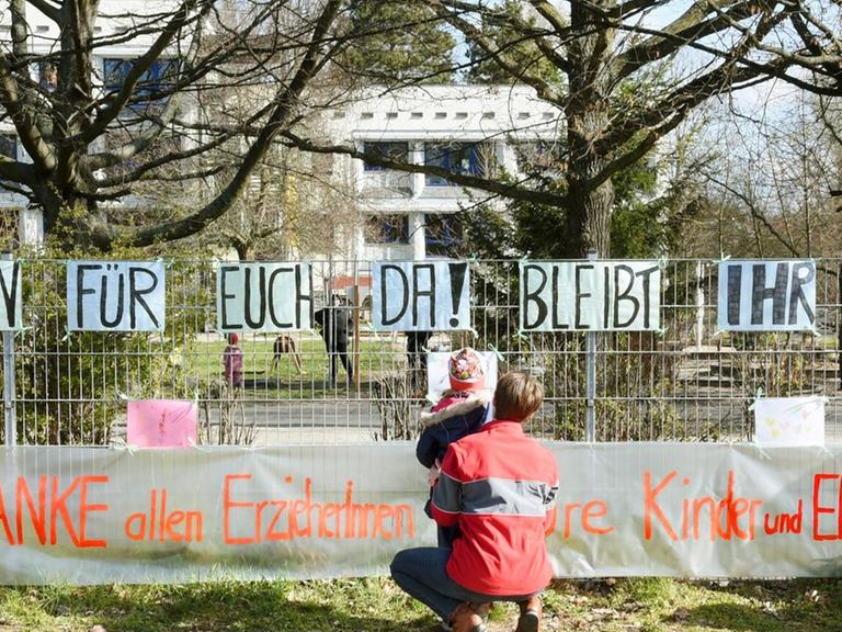 In der Kindertagesstätte "Fuchsbau" vom DRK-Kreisverband Leipzig befestigen Erzieherinnen mit ihren vier- und fünfjährigen Kindern selbstgemalte Bilder am Zaun der Einrichtung. Eltern hatten in der Nacht bereits ein Schriftband angebracht, auf dem "Danke allen ErzieherInnen - Eure Kinder und Eltern" angebracht.