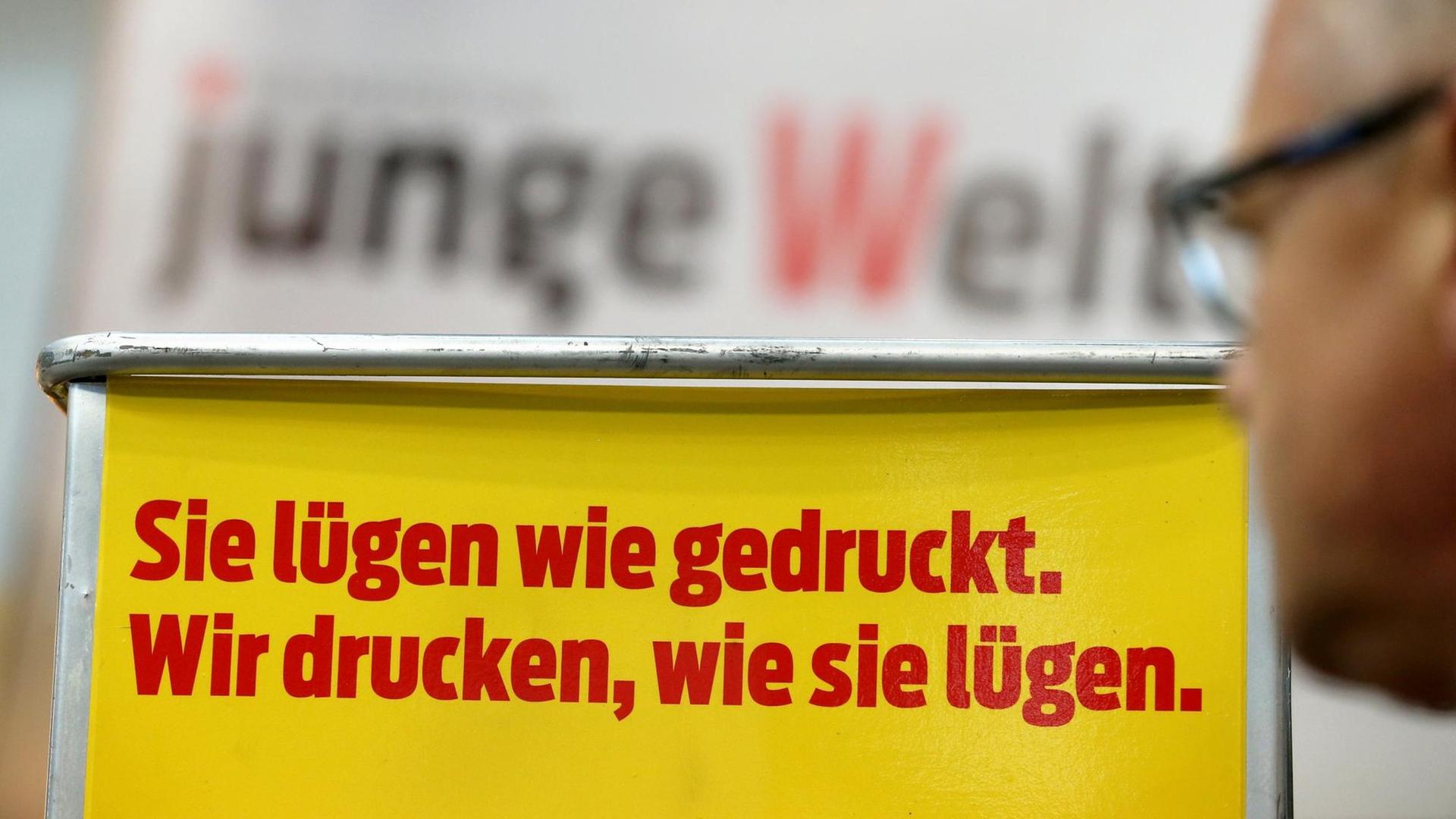 Ein Messebesucher steht am am Stand der Zeitung "Junge Welt" an einem Regal auf der Buchmesse in Leipzig Ein Messebesucher steht am am Stand der Zeitung "Junge Welt" an einem Regal auf der Buchmesse in Leipzig