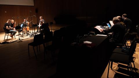 Links spielt das Quartett auf der Bühne und im Zuschauerraum sitzen Tonmeister an Bildschirmen, die den Sound live bearbeiten.