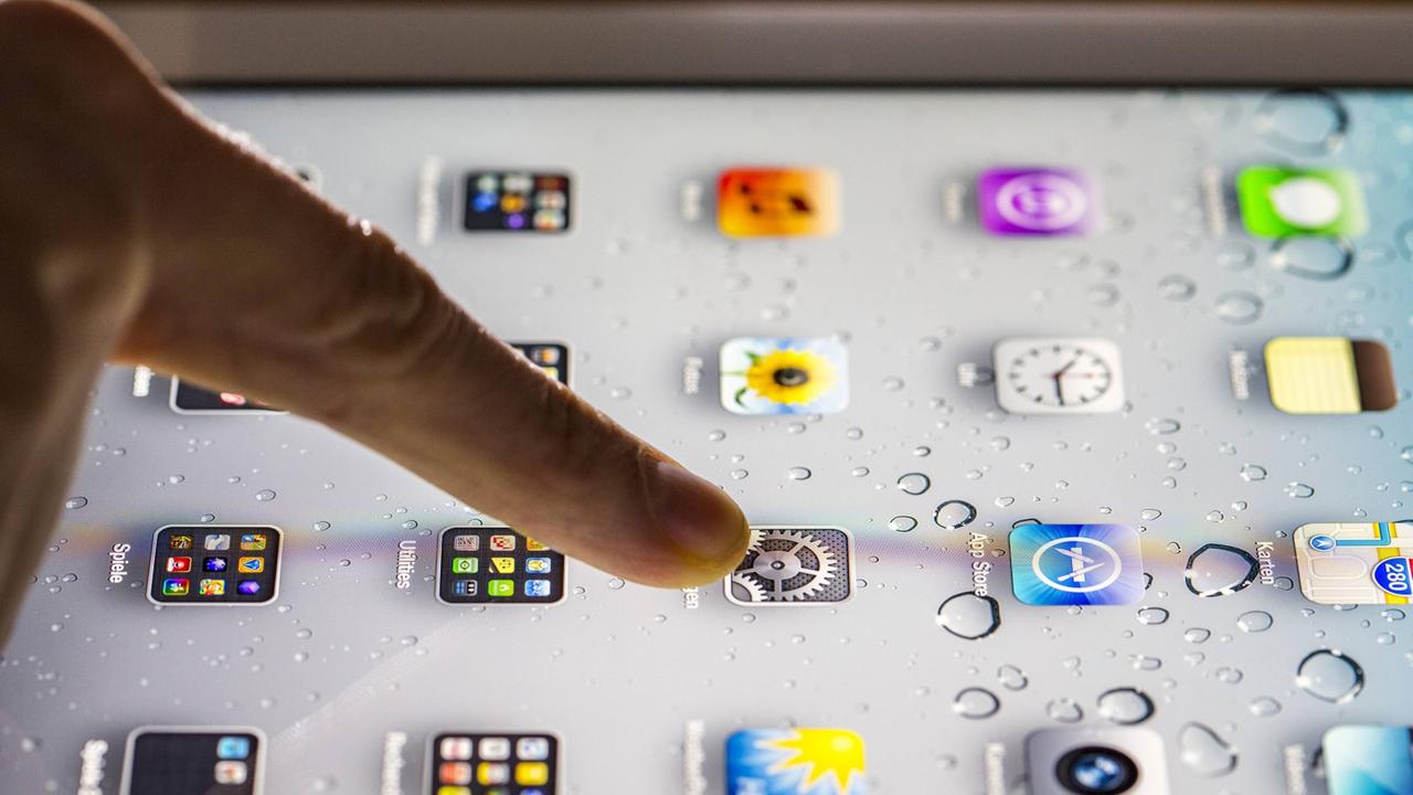 Eine Person tippt mit dem Finger auf ein Tablet. Eine Person tippt mit dem Finger auf ein Tablet.