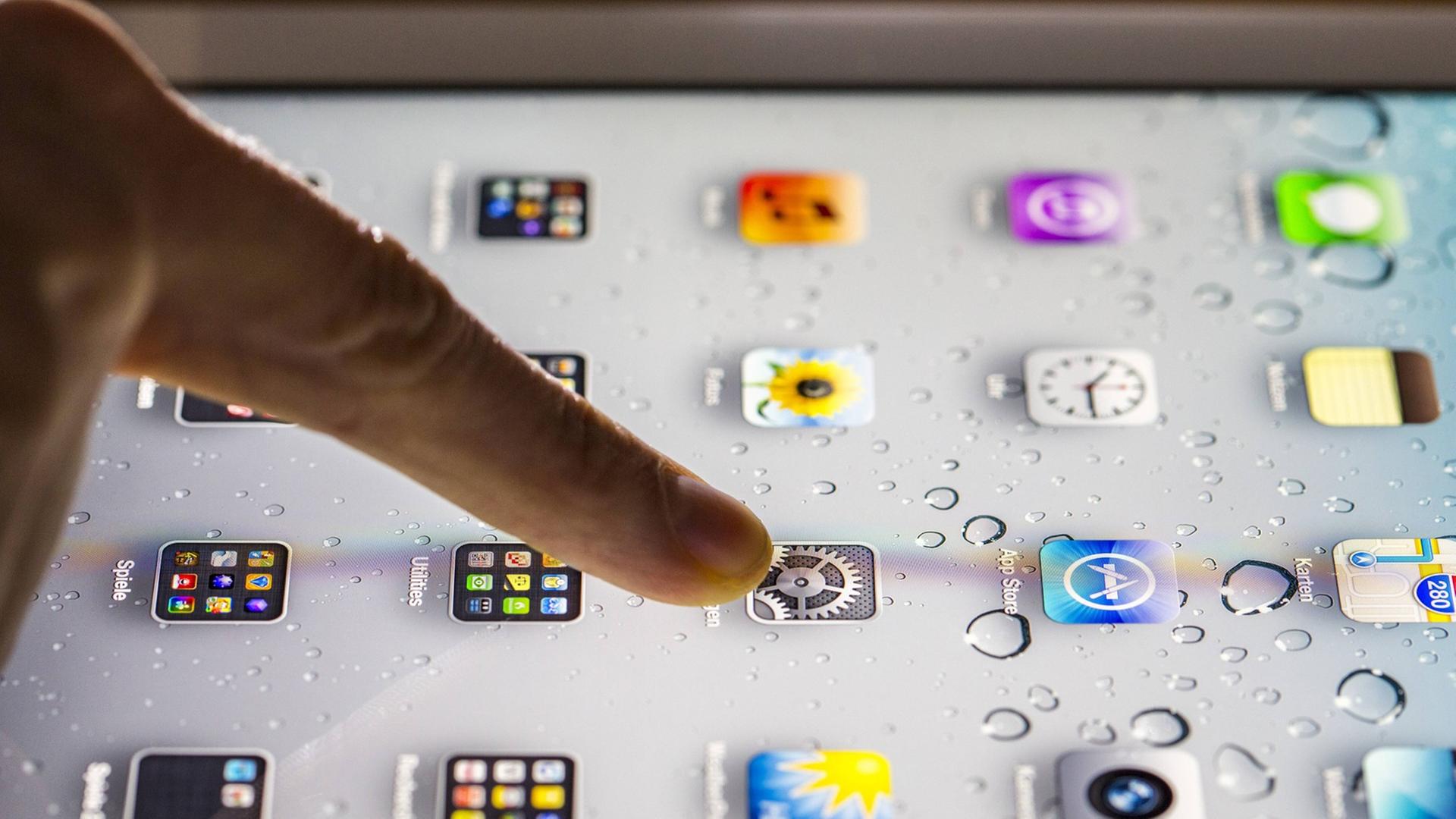 Eine Person tippt mit dem Finger auf ein Tablet. Eine Person tippt mit dem Finger auf ein Tablet.