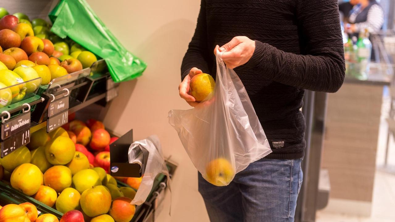 Ein Mann packt in einem Supermarkt in Flensburg Obst in einen Plastikbeutel Ein Mann packt in einem Supermarkt in Flensburg Obst in einen Plastikbeutel