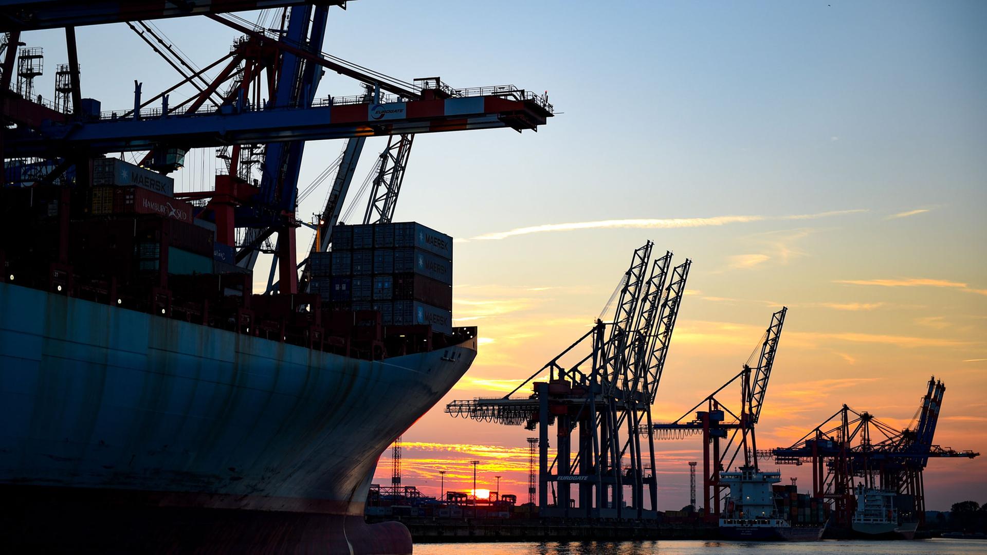 Die Sonne geht in Hamburg im Hafen hinter den Kränen der Containerverladung unter. Die Sonne geht in Hamburg im Hafen hinter den Kränen der Containerverladung unter.