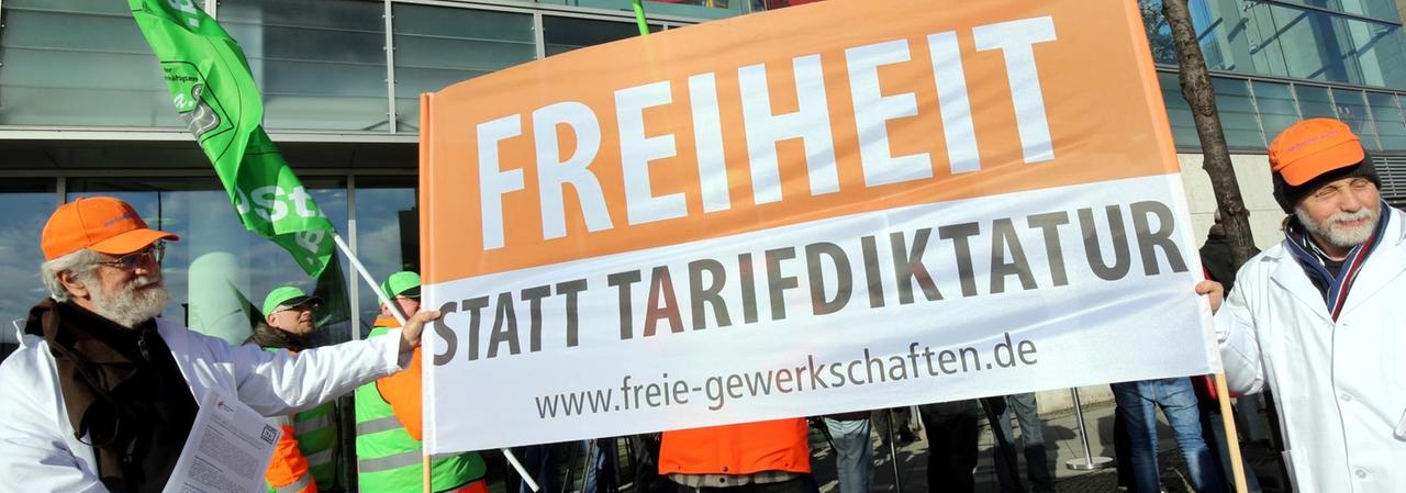 Teilnehmer einer Mahnwache von dbb Beamtenbund und Tarifunion gegen eine Zwangs-Tarifeinheit halten am 02.03.2015 vor der CDU-Parteizentrale in Berlin ein Plakat mit der Aufschrift "Freiheit statt Tarifdiktatur".