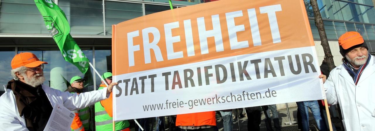 Teilnehmer einer Mahnwache von dbb Beamtenbund und Tarifunion gegen eine Zwangs-Tarifeinheit halten am 02.03.2015 vor der CDU-Parteizentrale in Berlin ein Plakat mit der Aufschrift "Freiheit statt Tarifdiktatur". Teilnehmer einer Mahnwache von dbb Beamtenbund und Tarifunion gegen eine Zwangs-Tarifeinheit halten am 02.03.2015 vor der CDU-Parteizentrale in Berlin ein Plakat mit der Aufschrift "Freiheit statt Tarifdiktatur".