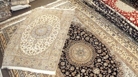 Perserteppiche werden von Mitarbeitern eines Ausstellers aus dem Iran in Hannover vor Beginn der Teppich-Messe Domotex sortiert