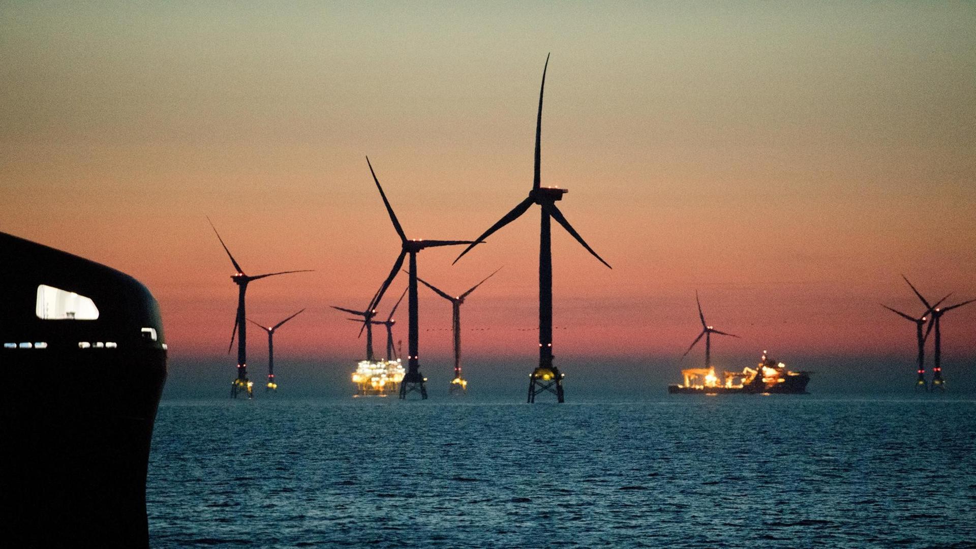Mehrere Windräder stehen in der Ostsee vor der Insel Rügen. Der Himmel strahlt rötlich. Mehrere Windräder stehen in der Ostsee vor der Insel Rügen. Der Himmel strahlt rötlich.