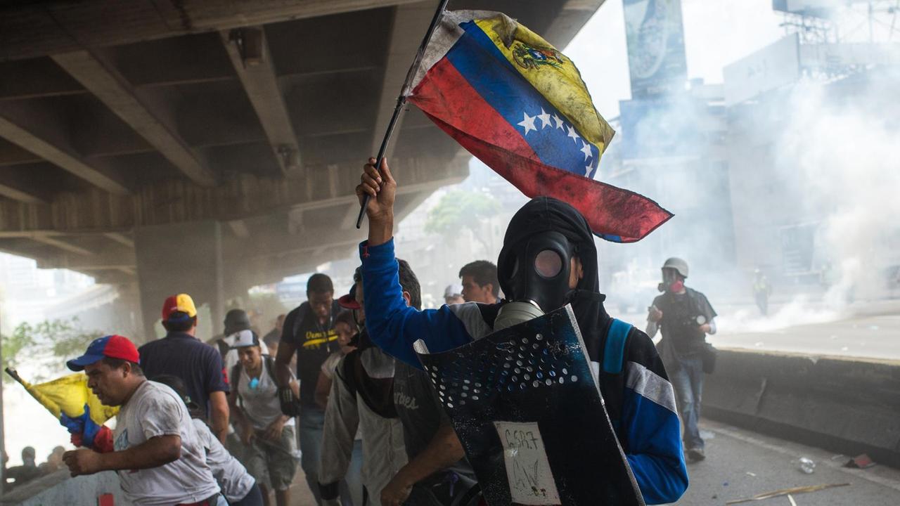Ein maskierter Demonstrant läuft vom Tränengas weg während einer Protest in Caracas, Venezuela, bei der es am 19.04.2017 zu Auseinandersetzungen kam. Die Opposition fordert Neuwahlen und macht Präsident Nicolas Maduro für die schwere politische und ökonomische Krise in dem Land mit den größten Ölreserven verantwortlich. Ein maskierter Demonstrant läuft vom Tränengas weg während einer Protest in Caracas, Venezuela, bei der es am 19.04.2017 zu Auseinandersetzungen kam. Die Opposition fordert Neuwahlen und macht Präsident Nicolas Maduro für die schwere politische und ökonomische Krise in dem Land mit den größten Ölreserven verantwortlich.