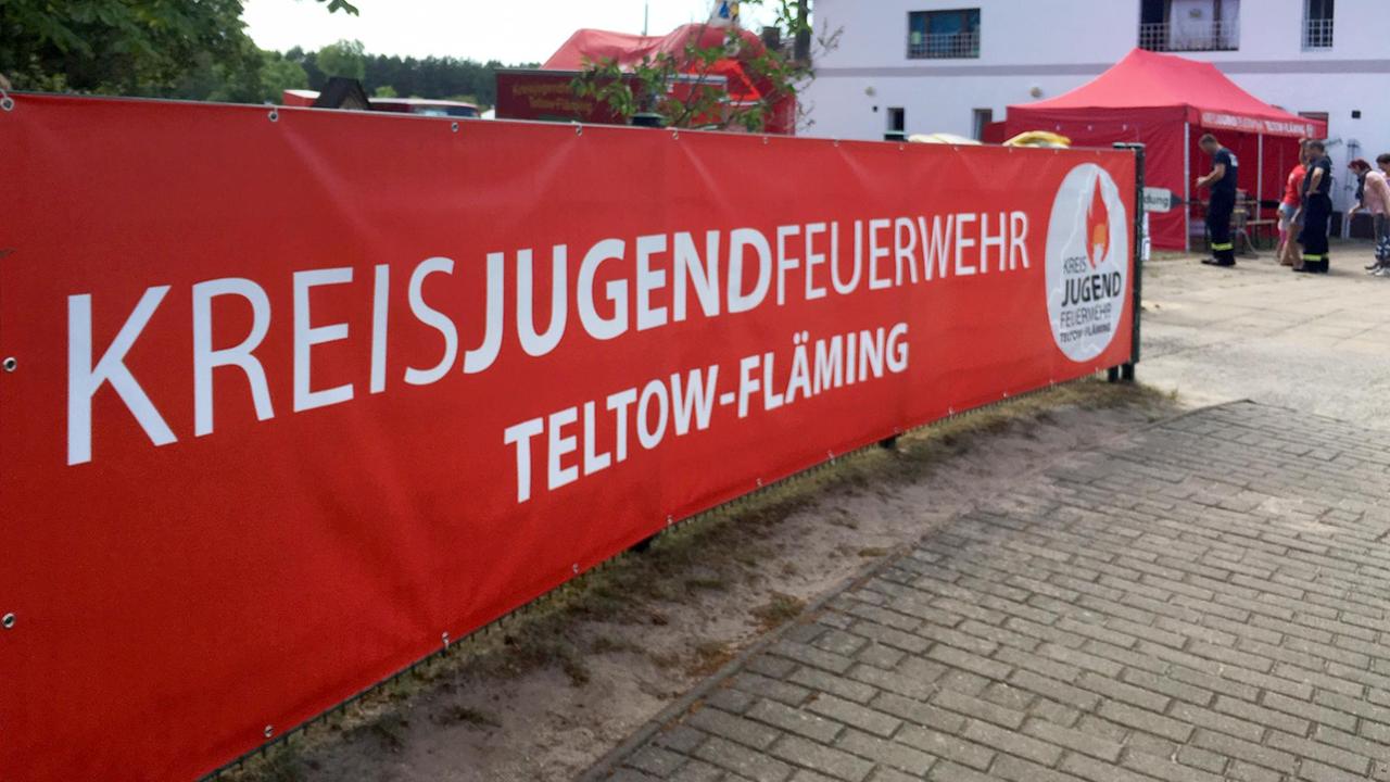 Banner der Kreisjugendfeuerwehr Teltow-Fläming, im Hintergrund das Feuerwehrgebäude. Banner der Kreisjugendfeuerwehr Teltow-Fläming, im Hintergrund das Feuerwehrgebäude.