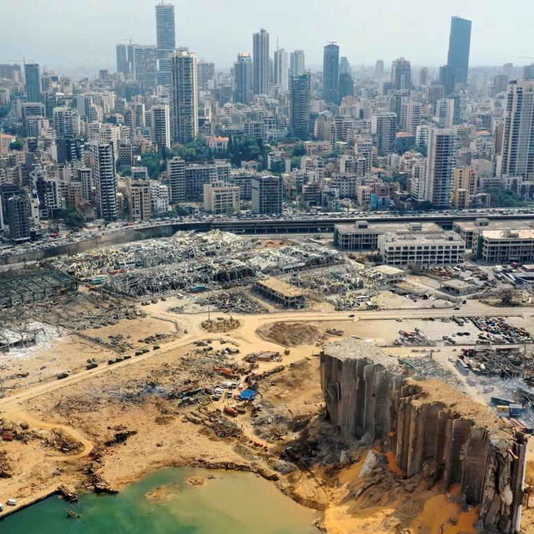 Blick auf den zerstörten Hafen von Beirut und die dahinterliegende Stadt.