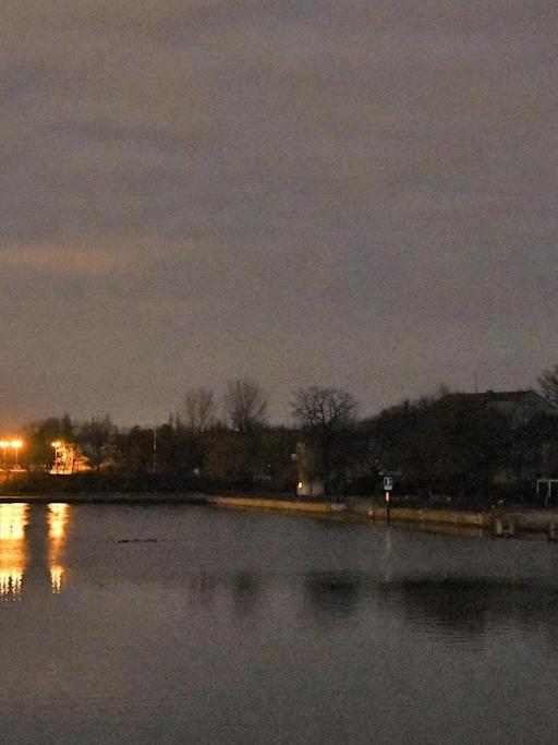 Eine Brücke über die Spree ist nachts beleuchtet, während am Ufer die Häuser und eine Kirche wegen eines Stromausfalls im Dunkeln liegen.