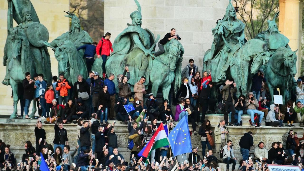 Junge Menschen protestieren auf dem Heldenplatz in Budapest und klettern dabei auch auf die alten Reiterstandbilder.