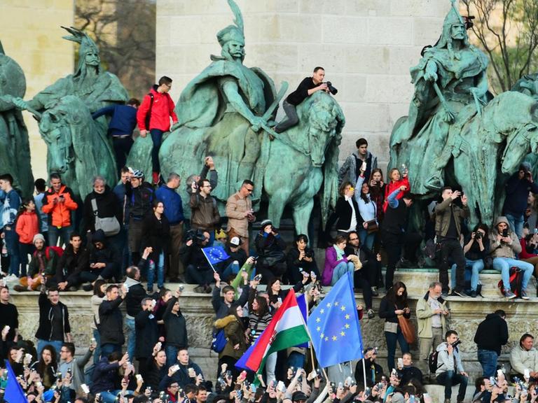 Junge Menschen protestieren auf dem Heldenplatz in Budapest und klettern dabei auch auf die alten Reiterstandbilder.