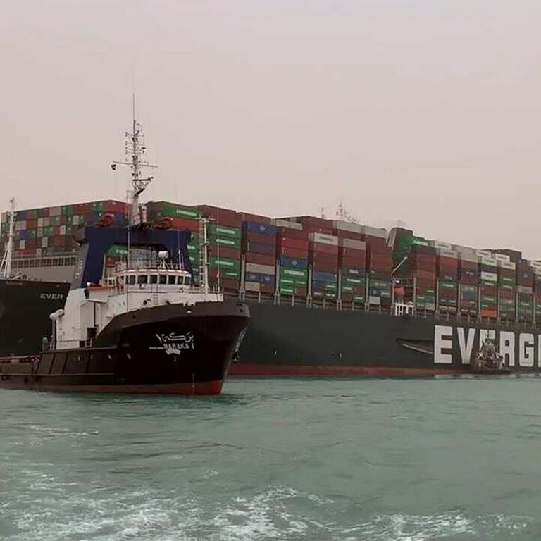 Schlepper vor dem auf Grund gelaufenen Containerschiff "Ever Given" im Suezkanal