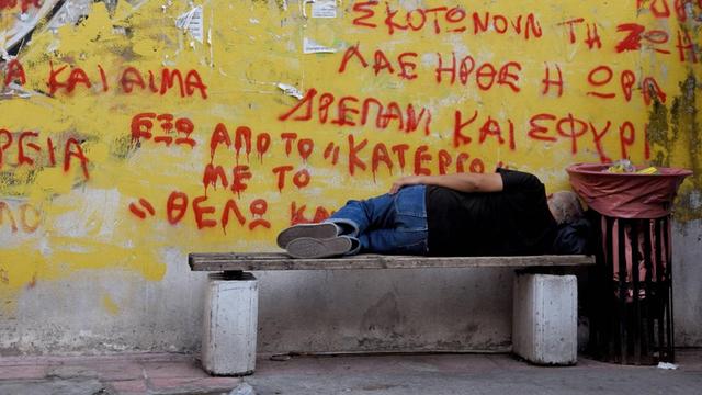 Piräus (Griechenland). im Hafenviertel: Ein Mann liegt auf einer Bank und schläft.