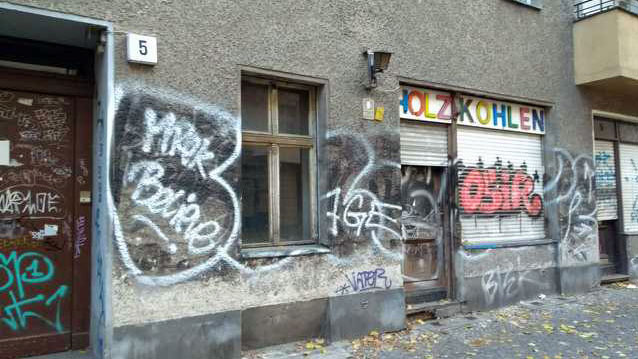 Blick auf eine Ladenwohnung mit dem Schild "Holzkohlen" in einem weitgehend leerstehenden Haus in Berlin-Neukölln.