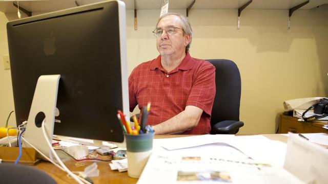 Rollie Atkinson, der Besitzer und Verleger der Healdsburg Tribune, einer Lokalzeitung in Kalifornien, sitzt an seinem Schreibtisch und schaut auf seinen Computer.