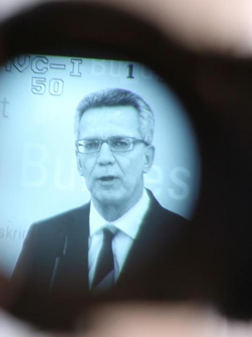 Bundesinnenminister Thomas de Maiziere (CDU) spricht am 02.10.2015 in einem Konferenzraum im BKA in Wiesbaden (Hessen) auf einer Pressekonferenz und ist dabei im Sucherbild einer Fernsehkamera zu sehen.