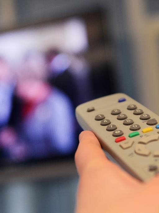Eine Fernbedienung wird am 09.01.2012 in Düsseldorf (Nordrhein-Westfalen) in Richtung eines Fernsehers gehalten.
