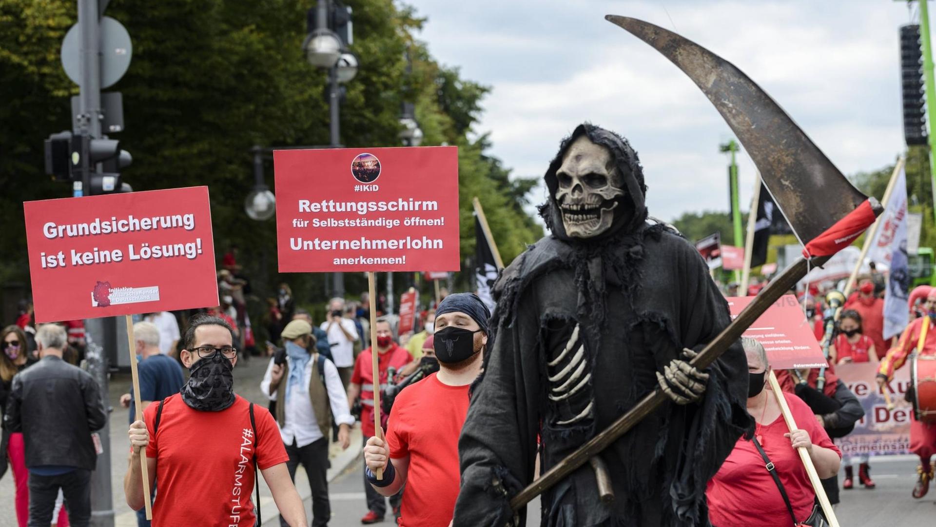 Rot gekleidete Protestierende der Veranstaltungsbranche ziehen durch Berlin, im Vordergrund ein als Sensenmann verkleideter Demonstrant Rot gekleidete Protestierende der Veranstaltungsbranche ziehen durch Berlin, im Vordergrund ein als Sensenmann verkleideter Demonstrant