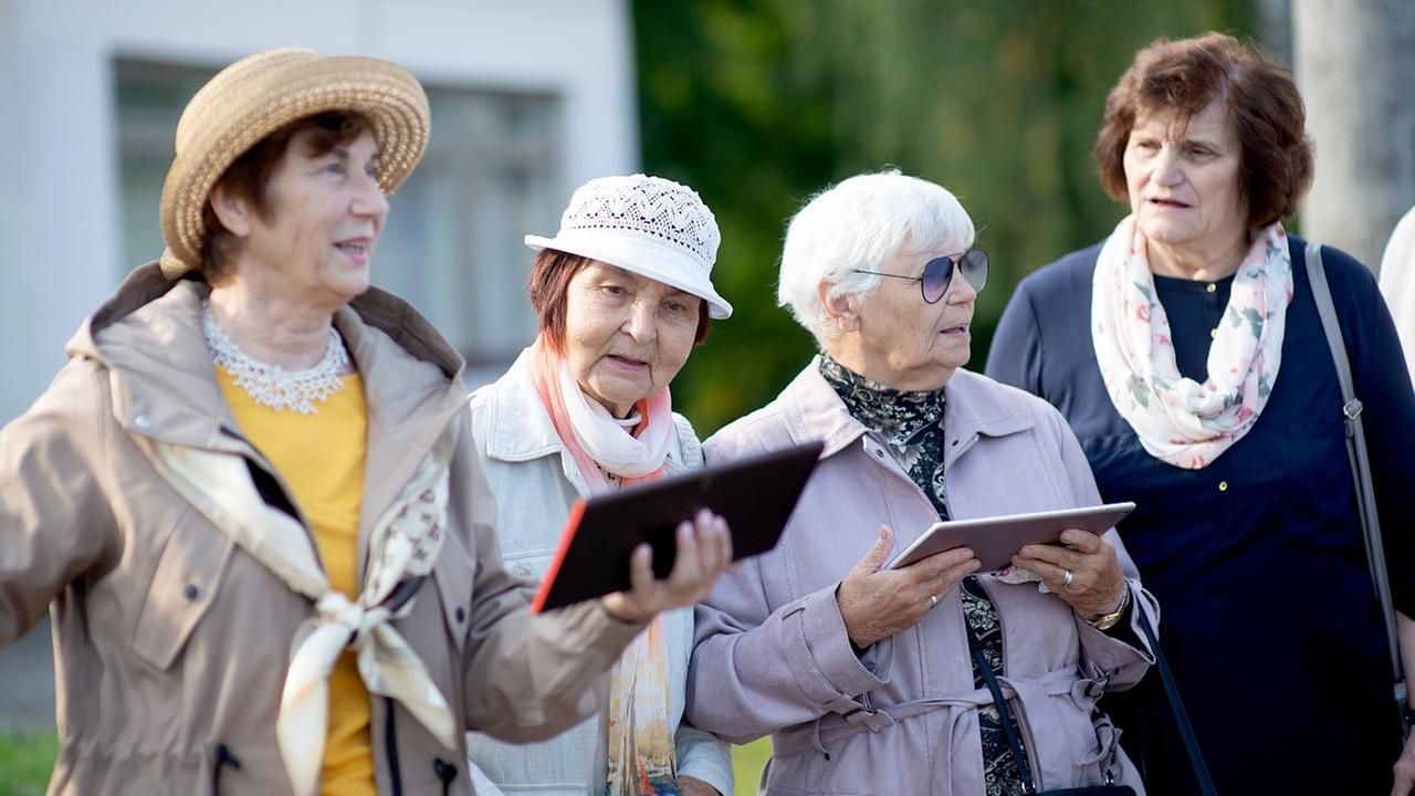 Eine Gruppe von Seniorinnen singt. Den Liedtext halten sie auf Tablets in der Hand. Eine Gruppe von Seniorinnen singt. Den Liedtext halten sie auf Tablets in der Hand.