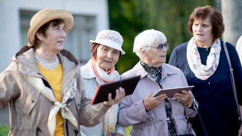 Eine Gruppe von Seniorinnen singt. Den Liedtext halten sie auf Tablets in der Hand.