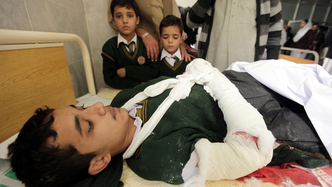 Ein junger Schüler liegt mit einem eingegipsten Arm in einem Krankenhaus.