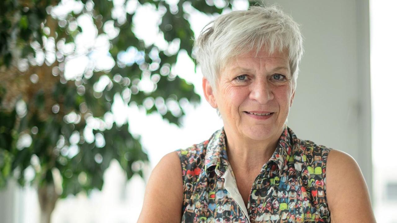 Barbara Unmüßig, Politologin und Vorstandsmitglied der Heinrich Böll Stiftung. Eine Frau mit kurzen Haaren sitzt in einem hellen Raum an einem Tisch. Barbara Unmüßig, Politologin und Vorstandsmitglied der Heinrich Böll Stiftung. Eine Frau mit kurzen Haaren sitzt in einem hellen Raum an einem Tisch.