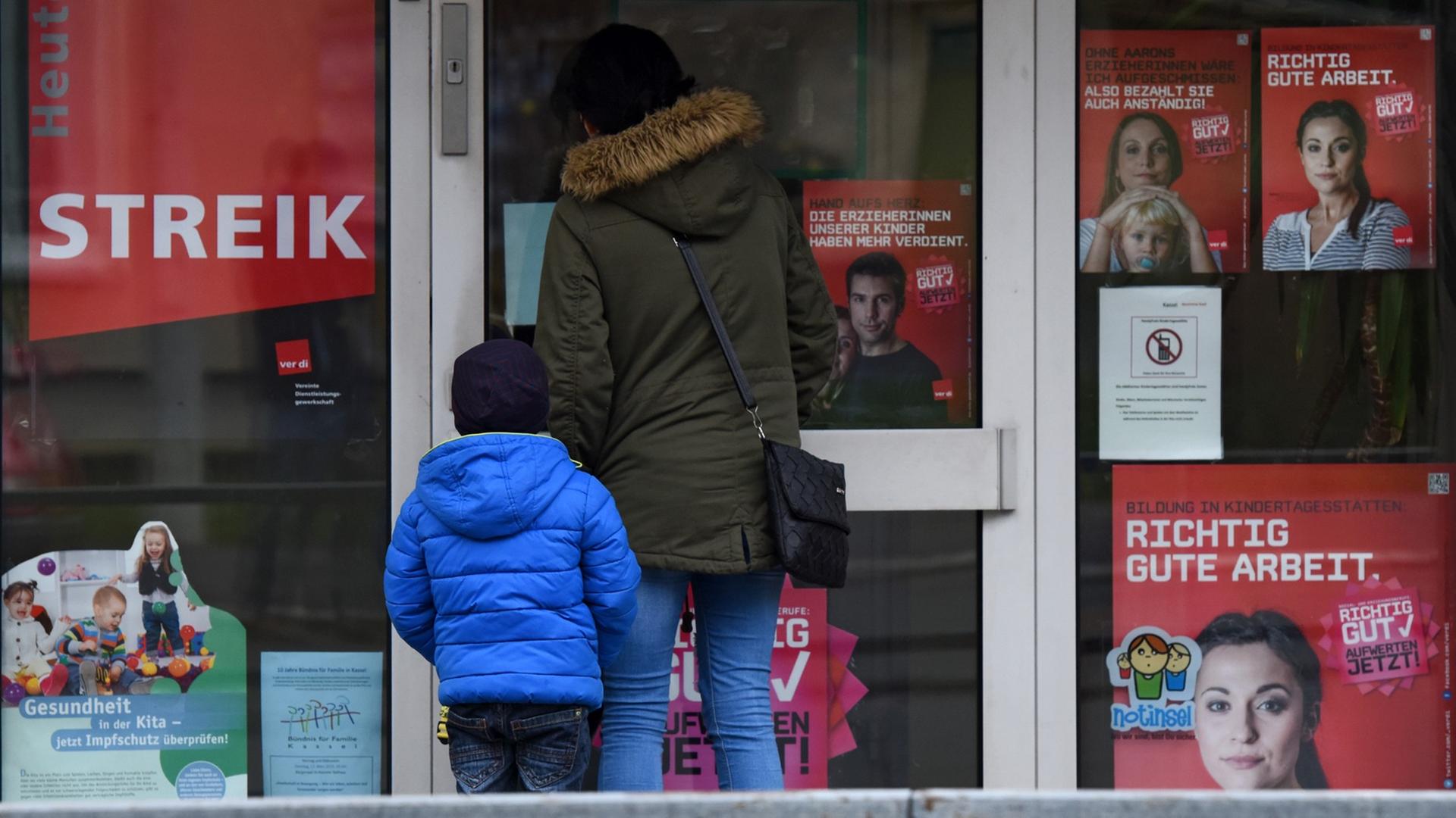 Eine Mutter steht mit ihrem Kind in Kassel (Hessen) vor einer geschlossenen Kita, an der Streik-Hinweise hängen Eine Mutter steht mit ihrem Kind in Kassel (Hessen) vor einer geschlossenen Kita, an der Streik-Hinweise hängen