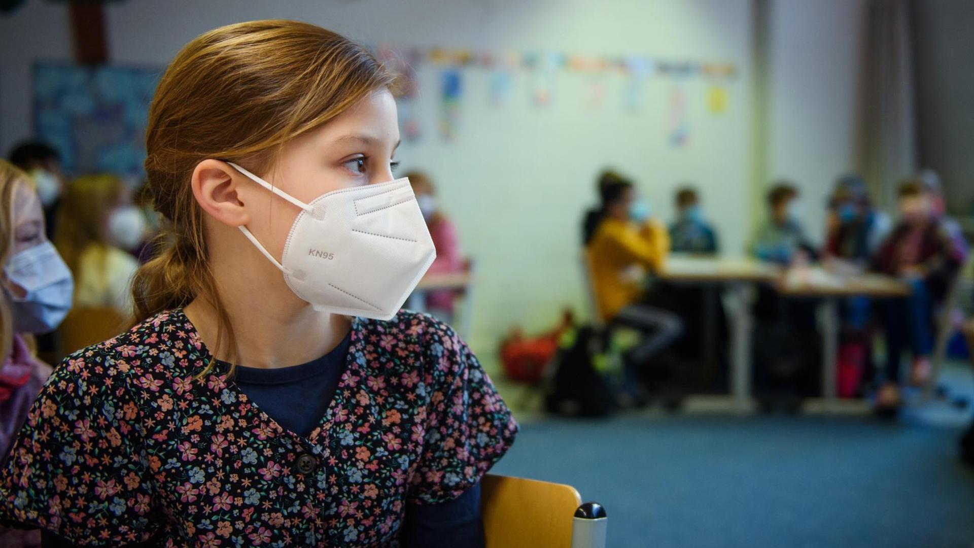 Eine Schülerin einer 4. Klasse sitzt im Unterricht an der Grundschule Russee in Kiel mit einer FFP-2-Maske an ihrem Platz. 