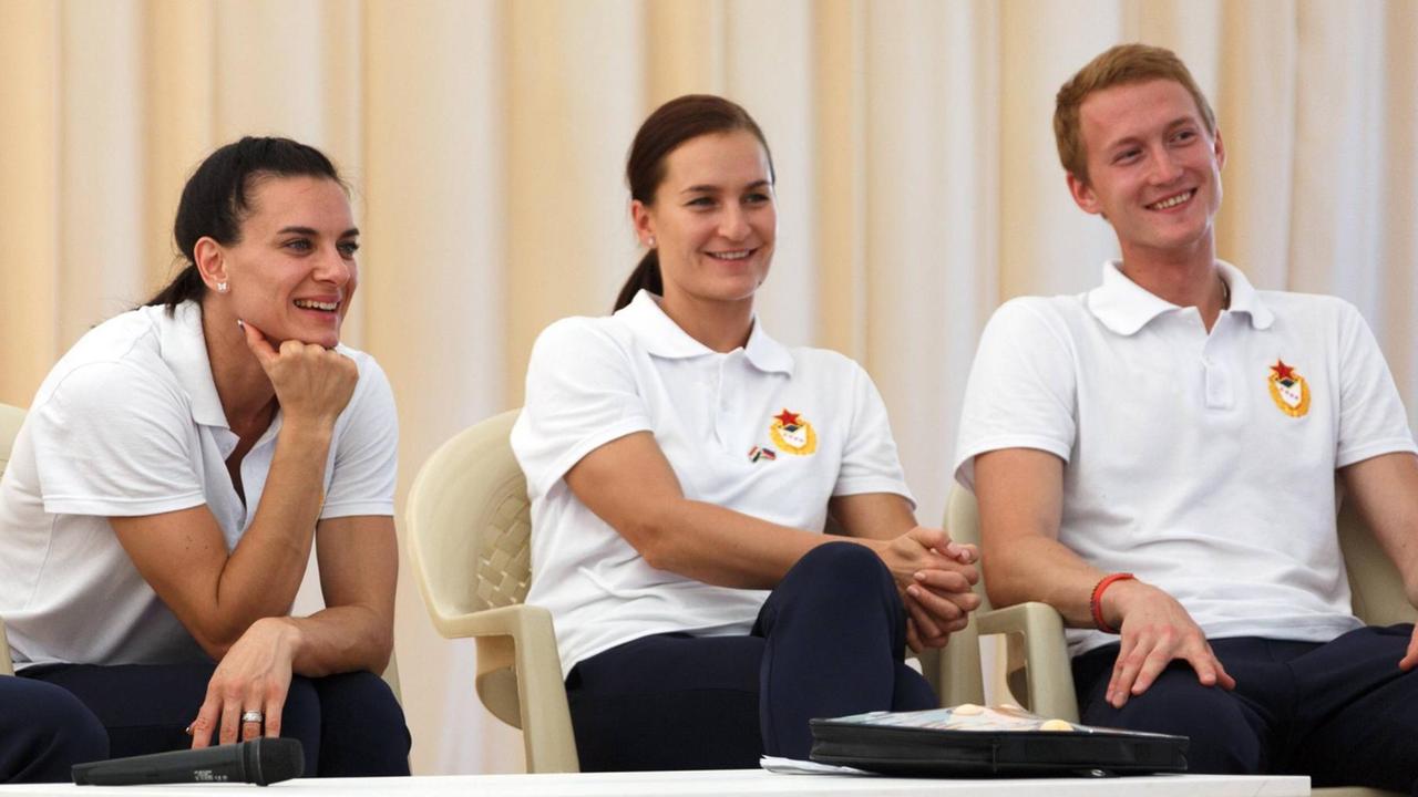 Ex-Stabhochspringerin und Athletensprecherin Jelena Issinbajewa (v.l.) Fechterin Sofia Welikaja, Fechter Artur Akhmatkhuzin sitzen nebeneinander auf Plastikstühlen. Ex-Stabhochspringerin und Athletensprecherin Jelena Issinbajewa (v.l.) Fechterin Sofia Welikaja, Fechter Artur Akhmatkhuzin sitzen nebeneinander auf Plastikstühlen.