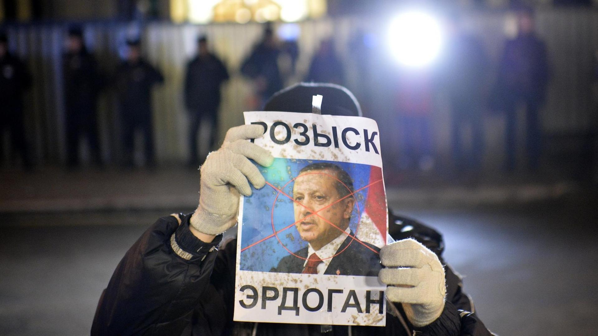 Ein Demonstrant hält ein Plakat des türkischen Präsidenten Erdogan in die Kamera. Über Erdogans Gesicht liegt ein rotes Kreuz wie von einem Zielradar. Ein Demonstrant hält ein Plakat des türkischen Präsidenten Erdogan in die Kamera. Über Erdogans Gesicht liegt ein rotes Kreuz wie von einem Zielradar.