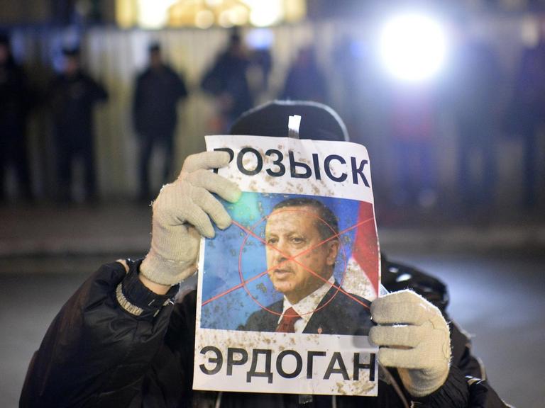 Ein Demonstrant hält ein Plakat des türkischen Präsidenten Erdogan in die Kamera. Über Erdogans Gesicht liegt ein rotes Kreuz wie von einem Zielradar.